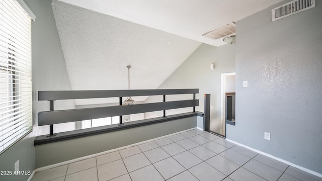 tiled spare room featuring lofted ceiling, visible vents, and baseboards