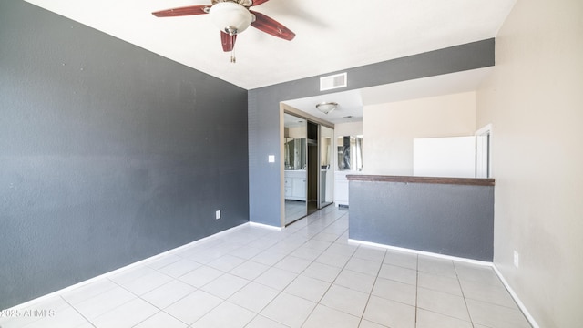 empty room featuring light tile patterned floors, ceiling fan, visible vents, and baseboards