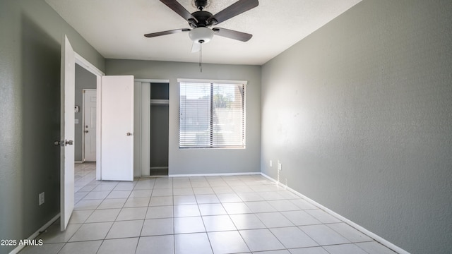 interior space featuring light tile patterned floors, a textured wall, ceiling fan, baseboards, and a closet