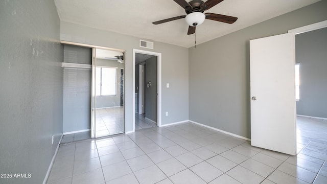 unfurnished bedroom featuring light tile patterned floors, baseboards, visible vents, and a closet