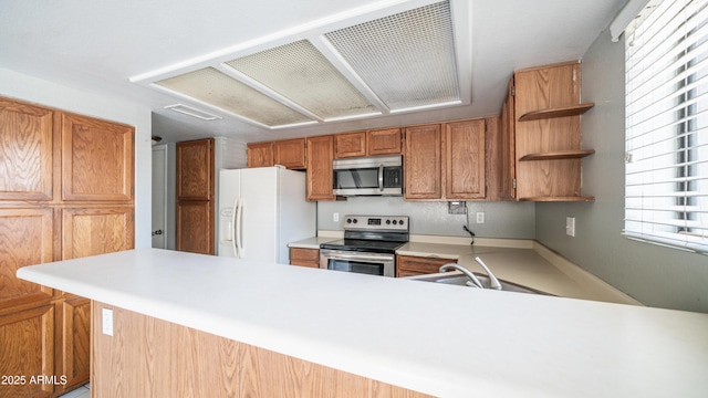 kitchen featuring open shelves, stainless steel appliances, light countertops, a sink, and a peninsula