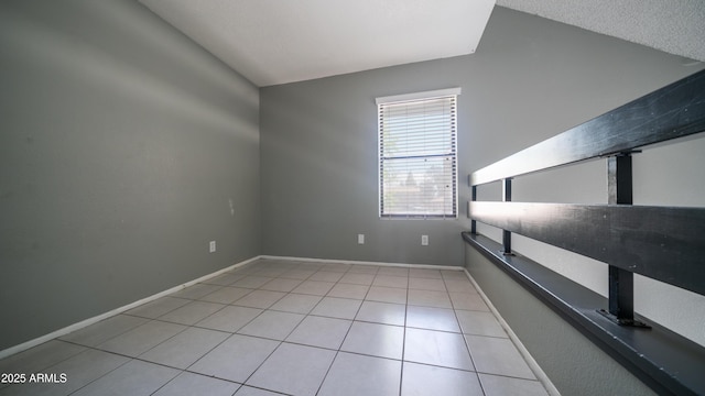 tiled spare room with lofted ceiling and baseboards