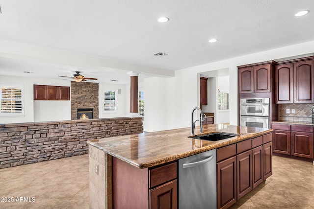 1755 E Tonto Dr, Chandler, AZ 85249 - kitchen with appliances with stainless steel finishes, ceiling fan, light stone counters, a fireplace, and backsplash