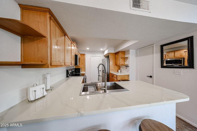 kitchen featuring a breakfast bar, appliances with stainless steel finishes, kitchen peninsula, and sink