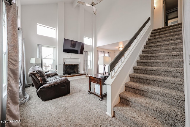 living room with a brick fireplace, high vaulted ceiling, and carpet