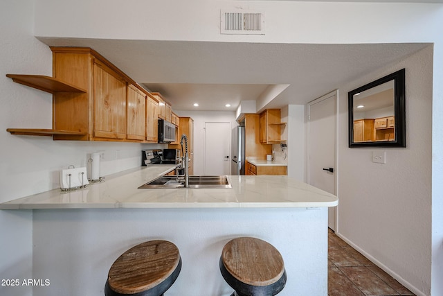 kitchen featuring a kitchen breakfast bar, stainless steel appliances, kitchen peninsula, and tile patterned floors