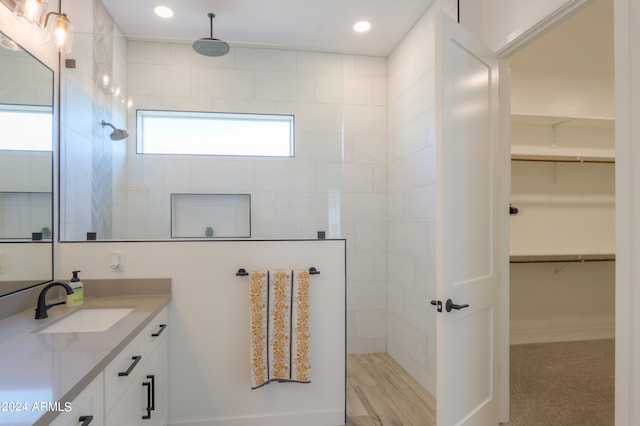 bathroom with vanity, plenty of natural light, a tile shower, and wood-type flooring