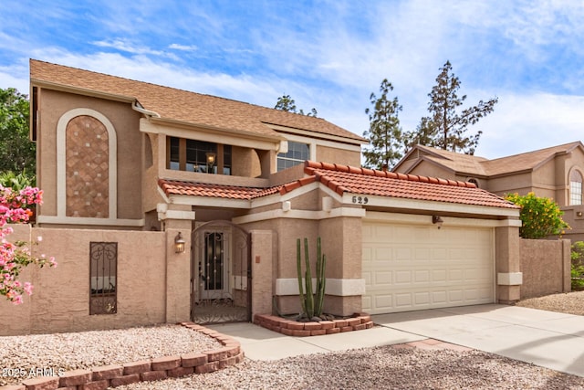 mediterranean / spanish house featuring stucco siding, a garage, driveway, and a tiled roof