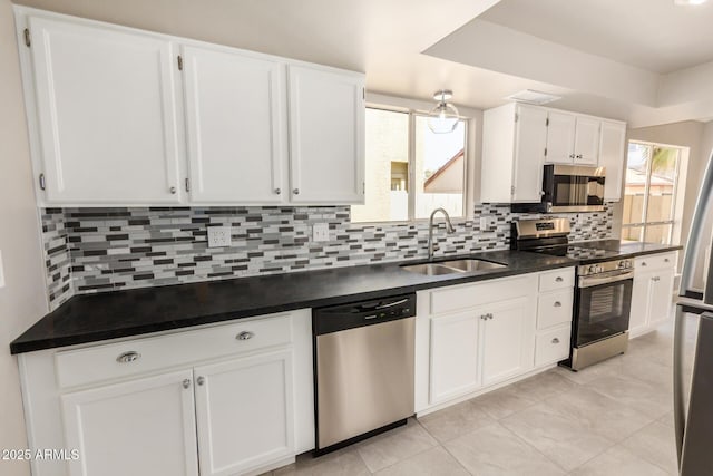 kitchen featuring stainless steel appliances, a sink, white cabinetry, and dark countertops