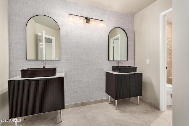 full bathroom featuring tile walls, two vanities, tile patterned flooring, toilet, and baseboards