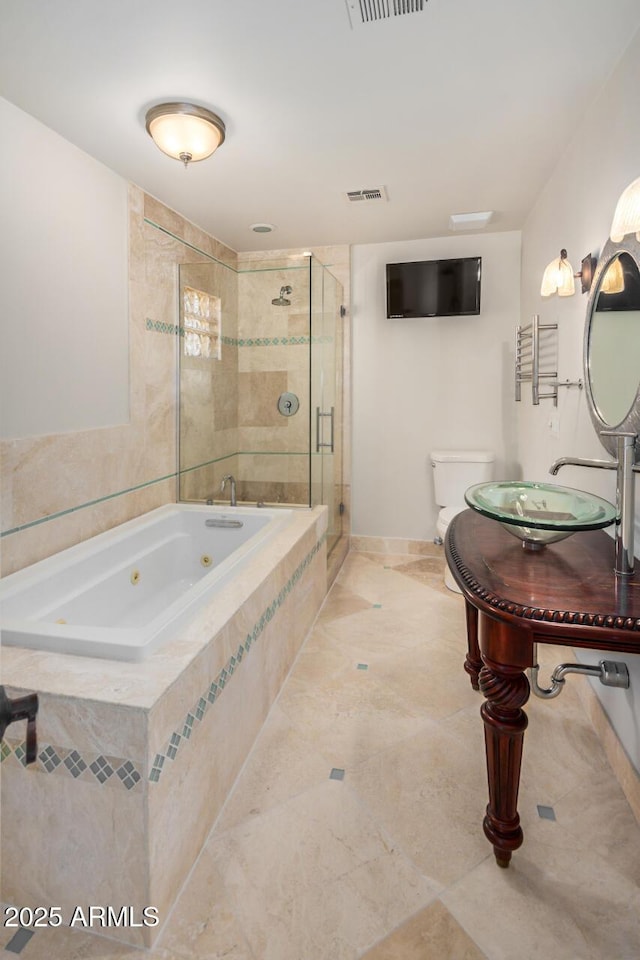 bathroom with a jetted tub, toilet, a shower stall, a sink, and tile patterned floors