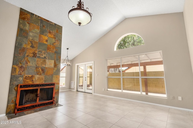 unfurnished living room featuring high vaulted ceiling, a tiled fireplace, baseboards, tile patterned floors, and french doors