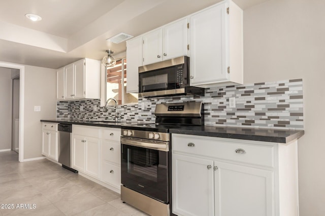 kitchen featuring appliances with stainless steel finishes, a sink, dark countertops, and decorative backsplash