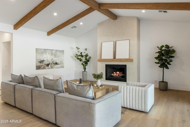 living room featuring light hardwood / wood-style flooring, lofted ceiling with beams, and a fireplace