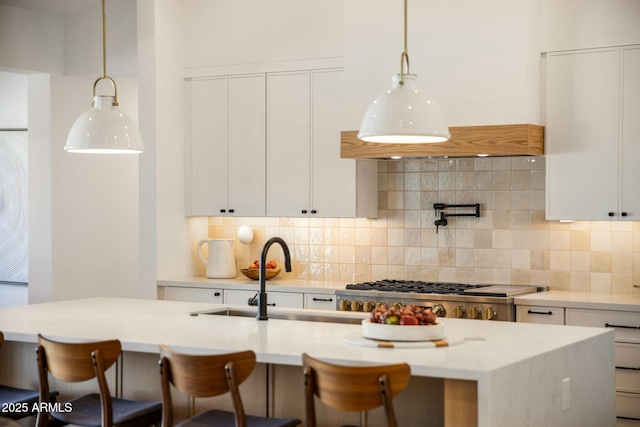 kitchen featuring decorative light fixtures, sink, white cabinetry, and tasteful backsplash