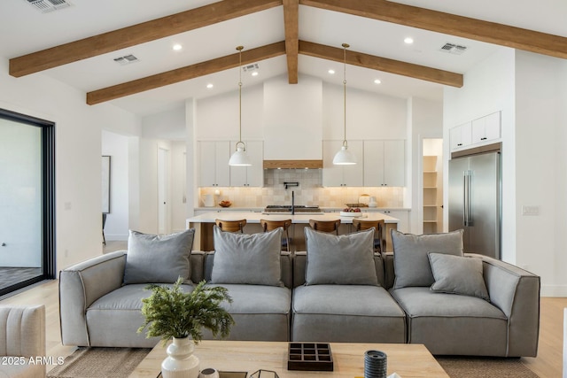 living room with high vaulted ceiling, sink, beamed ceiling, and light hardwood / wood-style floors