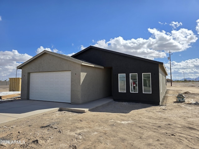 view of front of house featuring an attached garage, concrete driveway, and stucco siding