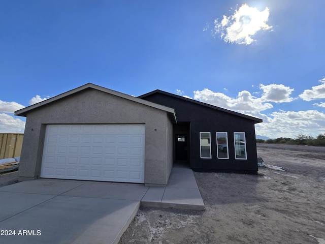 view of front facade featuring an attached garage, driveway, and stucco siding