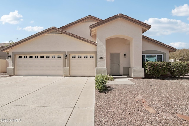 mediterranean / spanish house featuring a garage, a tile roof, driveway, and stucco siding