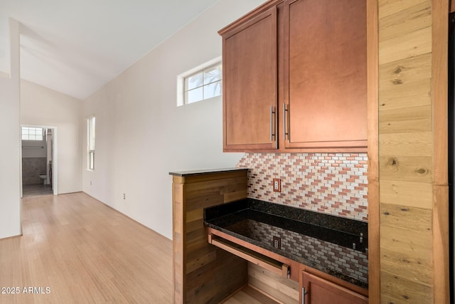 kitchen with lofted ceiling, light wood finished floors, plenty of natural light, and decorative backsplash