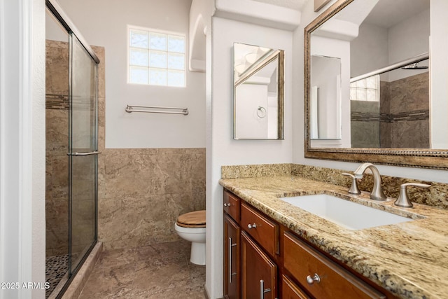 full bath with toilet, tile walls, a shower stall, and vanity