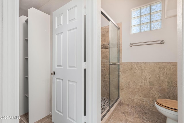 full bathroom with a stall shower, tile walls, and toilet