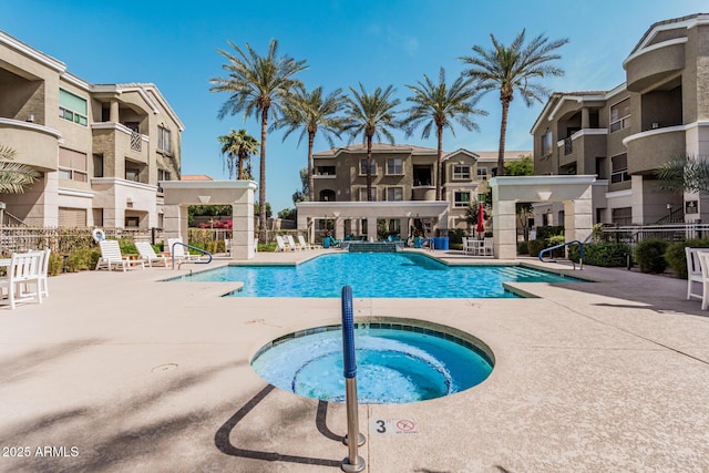 pool with a patio, fence, and a hot tub