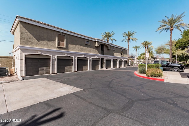 exterior space with central AC, community garages, and stucco siding