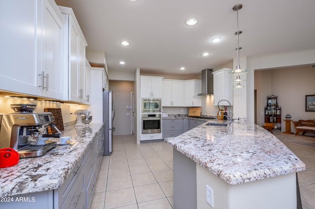 kitchen featuring wall chimney exhaust hood, white cabinetry, stainless steel appliances, and gray cabinetry