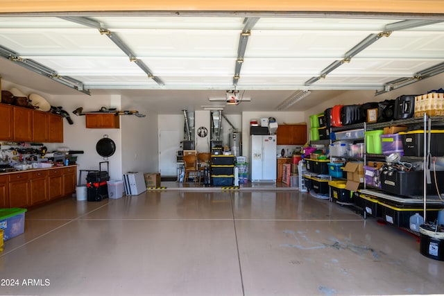 garage with gas water heater, white refrigerator with ice dispenser, and a garage door opener