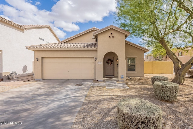 mediterranean / spanish home with a garage, driveway, a tile roof, fence, and stucco siding