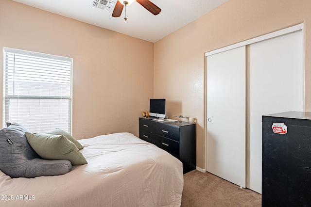 bedroom featuring a ceiling fan, visible vents, a closet, and light colored carpet