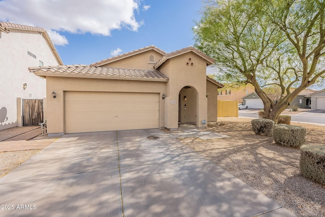 mediterranean / spanish-style house with driveway, a tiled roof, a garage, and stucco siding