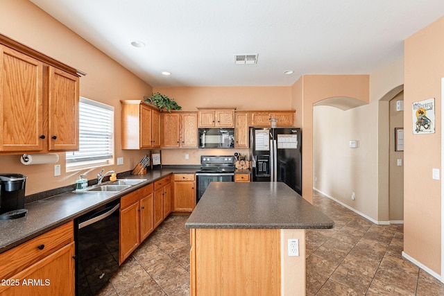 kitchen with arched walkways, dark countertops, visible vents, a sink, and black appliances