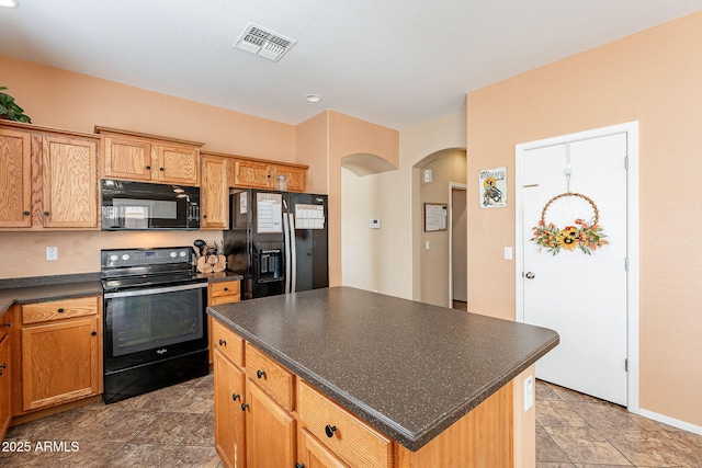 kitchen featuring arched walkways, a kitchen island, visible vents, black appliances, and dark countertops