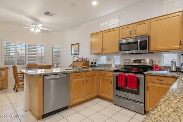 kitchen with light stone counters, sink, stainless steel appliances, and kitchen peninsula