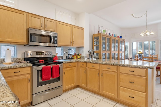 kitchen featuring light brown cabinetry, kitchen peninsula, stainless steel appliances, light stone countertops, and an inviting chandelier