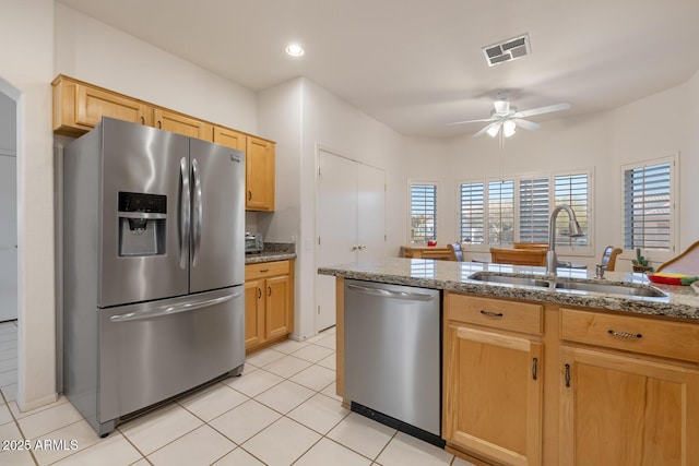 kitchen featuring appliances with stainless steel finishes, sink, ceiling fan, light stone countertops, and light brown cabinets