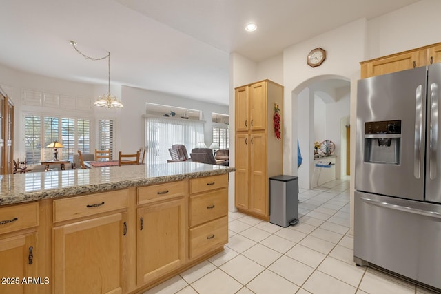 kitchen featuring pendant lighting, stainless steel refrigerator with ice dispenser, light stone counters, light tile patterned flooring, and light brown cabinets