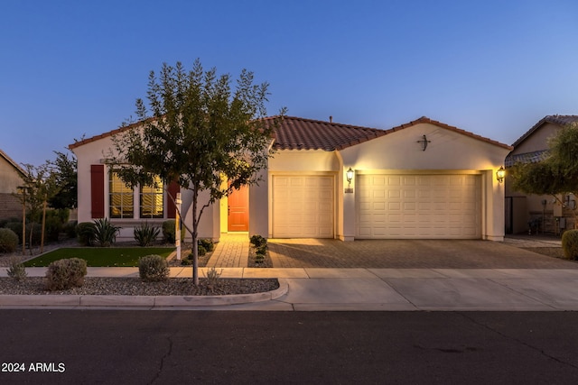 view of front of property with driveway, stucco siding, a tile roof, and a garage