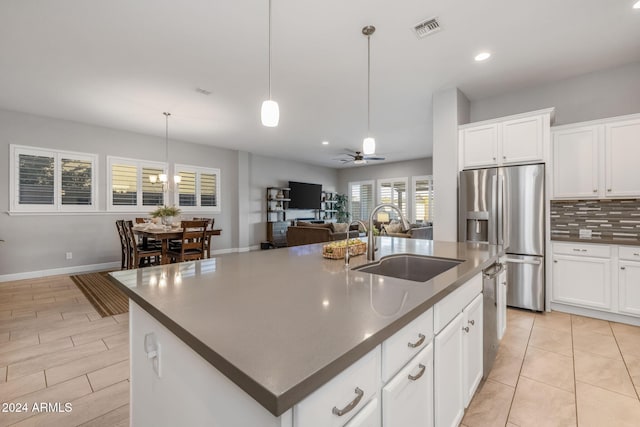 kitchen featuring a kitchen island with sink, ceiling fan, decorative light fixtures, sink, and appliances with stainless steel finishes