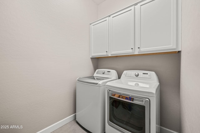 clothes washing area with cabinet space, baseboards, and washing machine and dryer