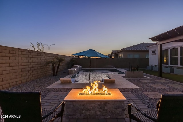 patio terrace at dusk with a fenced backyard and an outdoor fire pit