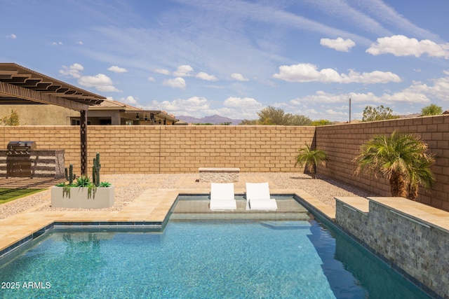 view of swimming pool featuring a mountain view, a fenced backyard, a grill, and a fenced in pool