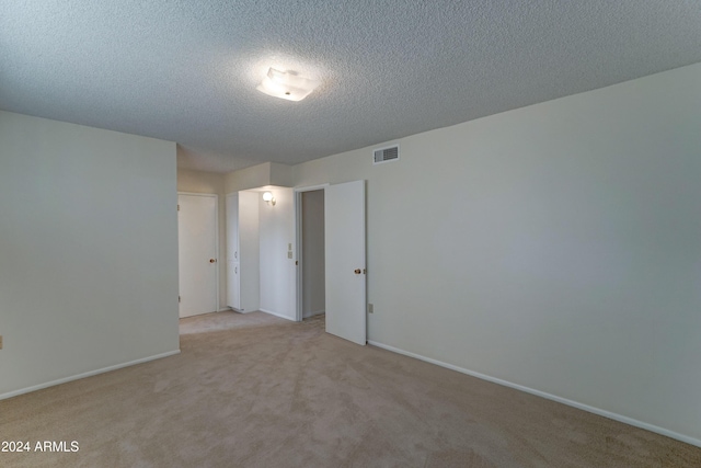 empty room featuring light colored carpet and a textured ceiling