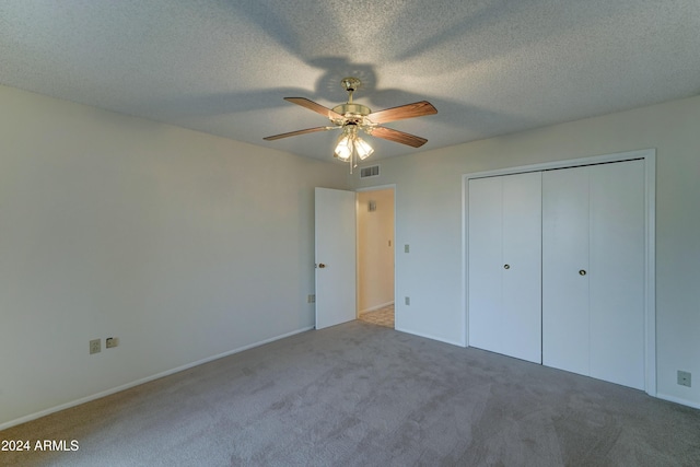 unfurnished bedroom with a textured ceiling, carpet floors, a closet, and ceiling fan