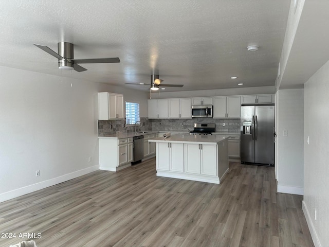 kitchen with light hardwood / wood-style floors, appliances with stainless steel finishes, ceiling fan, and a kitchen island