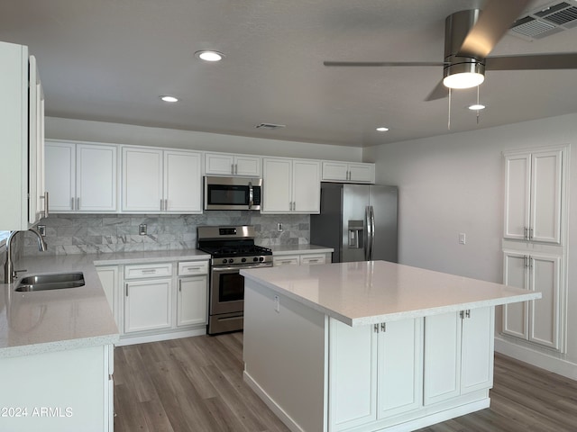 kitchen with stainless steel appliances, tasteful backsplash, sink, a kitchen island, and ceiling fan