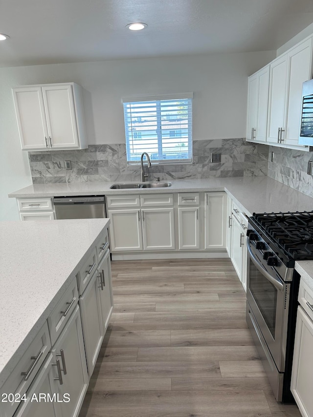 kitchen featuring sink, tasteful backsplash, light hardwood / wood-style flooring, and appliances with stainless steel finishes