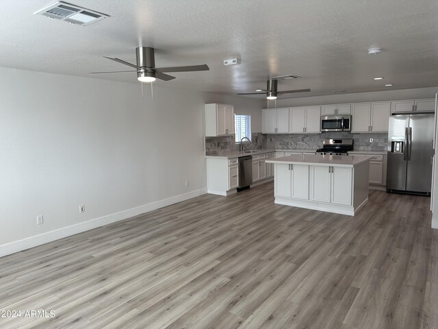 kitchen featuring ceiling fan, light hardwood / wood-style floors, sink, a center island, and stainless steel appliances